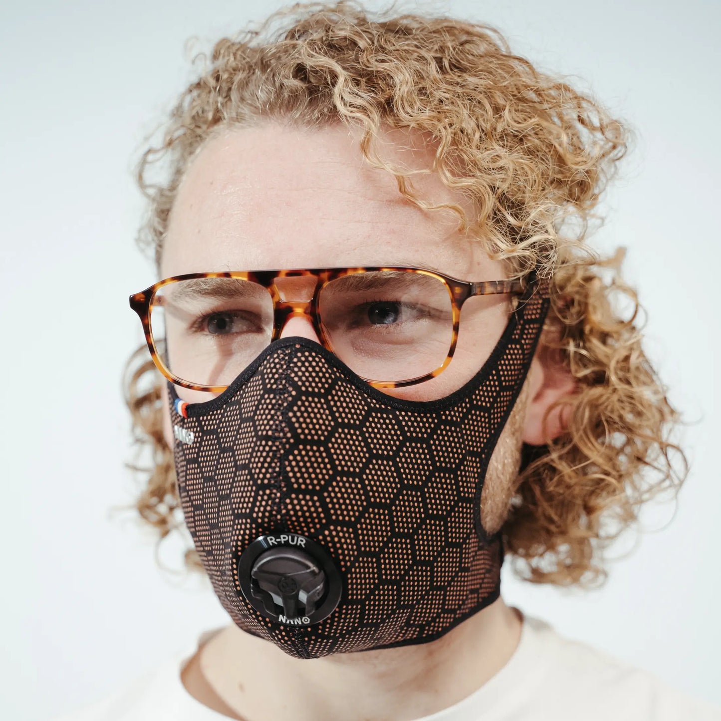 Man wearing a orange R-PUR mask, orange glasses and look at the back.