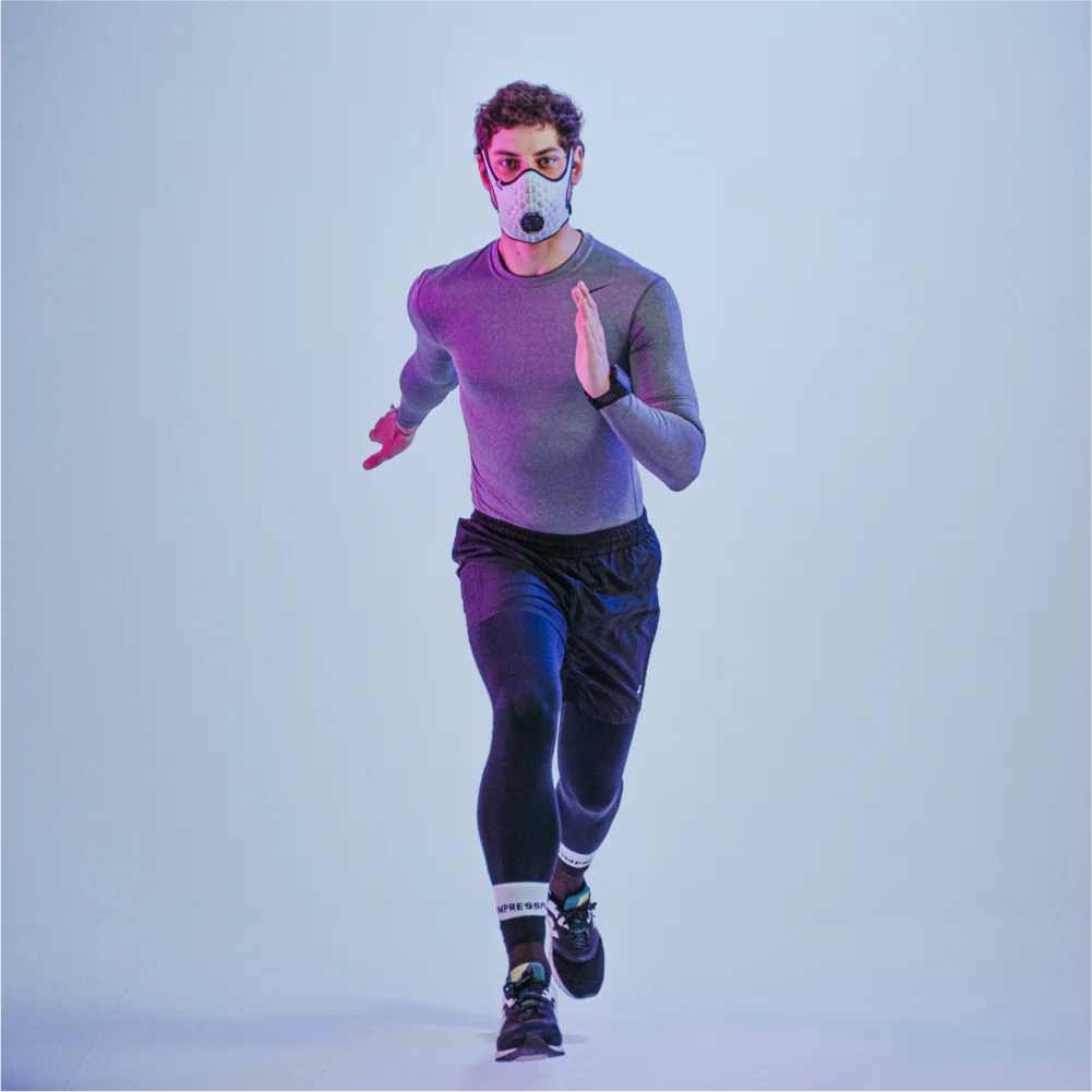 Runner wearing a white R-PUR running mask looking straight ahead and running toward the camera